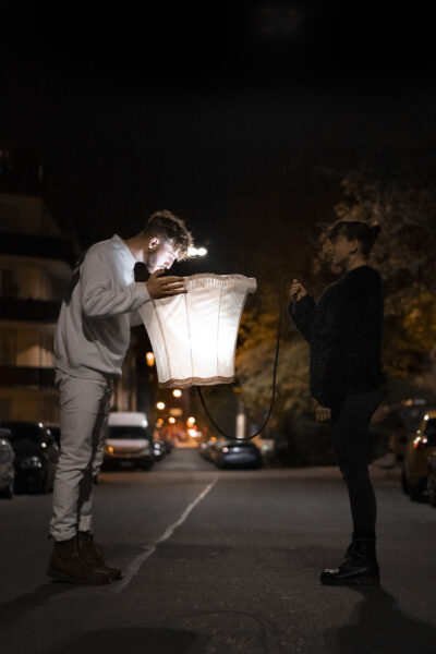 zwei Personen auf einer Straße mit leuchtendem Lampenschirm